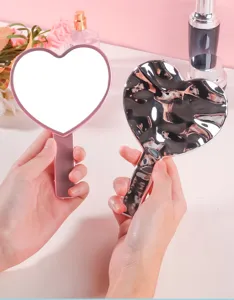 Primer plano de espejo de mano en forma de corazón con parte trasera de efecto ondas