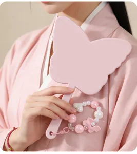 Detail view of a pink butterfly handheld makeup mirror with a cute beaded pendant.