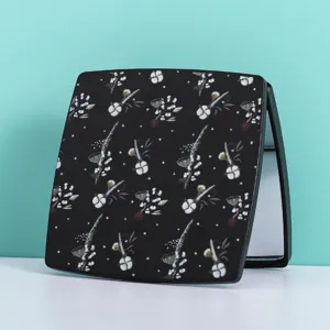 Detailansicht eines tragbaren Klappspiegels mit elegantem Blumenmuster auf schwarzer Hülle