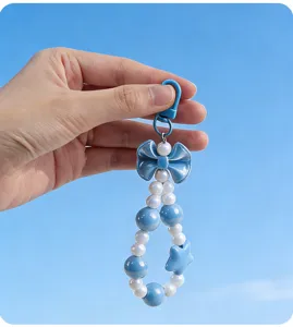Detail of a blue and white beaded charm with a bow and star against a clear blue sky.