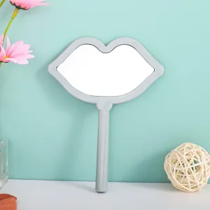 Detailed view of a stylish lip-shaped handheld makeup mirror with a sleek gray frame.