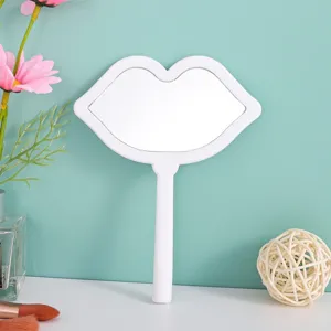 Close-up detail of a white lip-shaped handheld makeup mirror on a stylish vanity setup