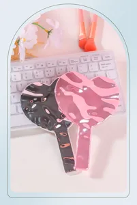 Vista detallada de un espejo de maquillaje portátil con forma de corazón y cromo rosa