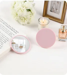 Detailed view of a portable round pink makeup mirror showing mirror and back on a vanity