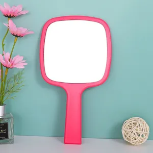 Detailopname van een roze handspiegel met afgeronde hoeken voor make-up.