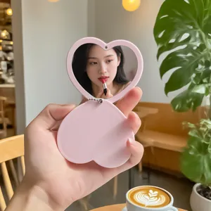 Portable pink heart-shaped swivel double-sided makeup mirror shown in cafe use