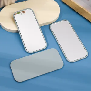 Set of three rectangular portable makeup mirrors with grey plastic frames on blue background
