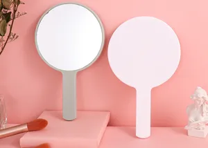 Detailweergave van grote ronde handheld make-up spiegels in grijs en wit op roze achtergrond