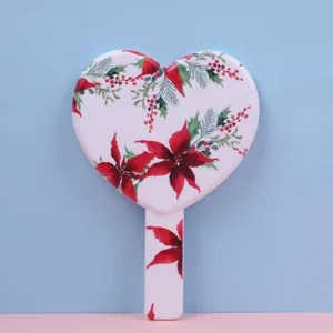 Detailed view of heart-shaped handheld makeup mirror with red poinsettia floral patterns