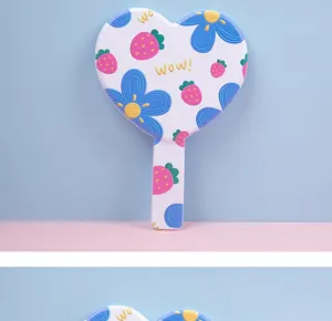 Detail view of cute heart-shaped handheld mirror with strawberry and flower patterns