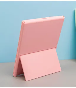 Back view of a pink portable folding three-fold makeup mirror standing on a desk surface