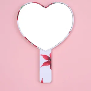 Heart-shaped handheld makeup mirror featuring a white frame with red floral leaf pattern