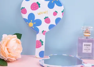 Detail of heart-shaped handheld mirror with embossed strawberry and flower patterns