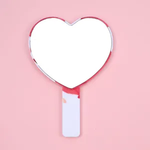 Close-up of heart-shaped handheld makeup mirror with pink marble pattern handle