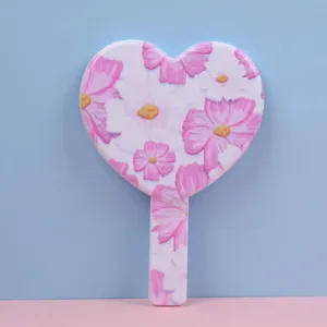 Detail view of heart-shaped handheld mirror featuring a delicate pink floral pattern design