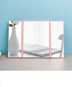 Detailed view of the elegant pink trifold portable makeup mirror on a clean desktop