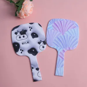 Close-up detail of portable hand-held mirrors featuring cow and purple shell patterns