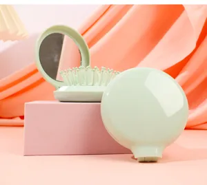 Close-up of portable mint green foldable hairbrush with integrated vanity mirror