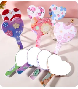 Various heart shaped handheld makeup mirrors with colorful floral patterns on back