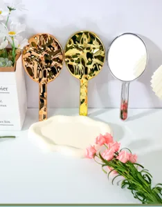 Nahaufnahme eleganter Handspiegel in Gold, Silber und Roségold mit Wellenstrukturen.