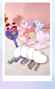 Detail view of various colorful heart-shaped handheld mirrors with floral patterns.