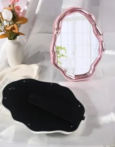 Macro view of an irregular pink cloud makeup mirror showing the foldable desktop stand