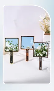 Close-up view of three portable handheld makeup mirrors with shiny electroplated frames.