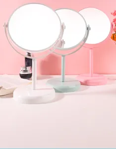 Detailweergave van roterende make-upspiegels in wit, groen en roze op een bureau.