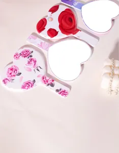 Detail view of heart-shaped hand mirrors with elegant rose patterns on white background