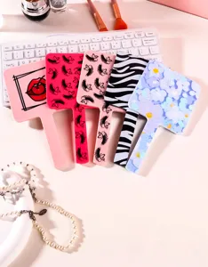 Divers miroirs à main aux motifs élégants disposés sur un bureau de maquillage blanc