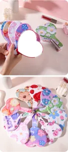 Detail of heart-shaped handheld makeup mirrors featuring colorful floral and embossed patterns