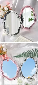 Close-up of silver and pink cloud-shaped makeup mirrors with irregular wavy frames