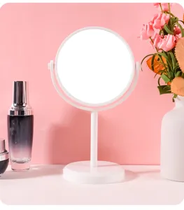 Elegante draaibare witte make-upspiegel op een roze achtergrond met bloemendecor
