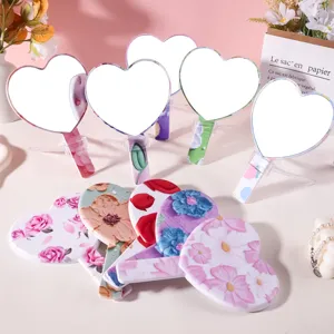 Heart-shaped handheld mirrors with vintage floral patterns on a soft pink background