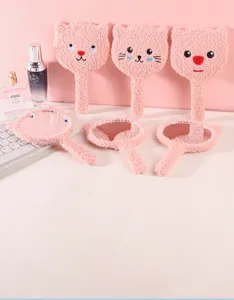 Group of pink plush cartoon bear and cat shaped handheld makeup mirrors on a desk