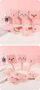 Macro detail of plush cartoon cat handheld mirrors in a soft pink fuzzy finish