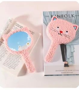 Close-up detail of a pink plush cat-shaped handheld mirror with soft fur texture.
