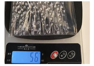 Imagen detallada de carámbanos navideños transparentes pesados en una báscula digital de 56g