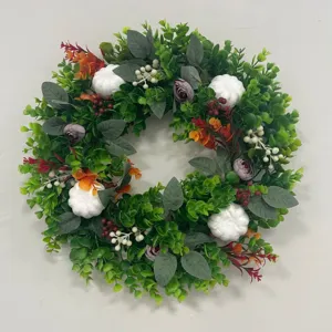 Vue détaillée d'une couronne d'automne en eucalyptus avec citrouilles et fleurs mauves.