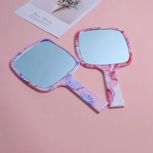 Close-up of portable handheld makeup mirrors with pink floral patterns.