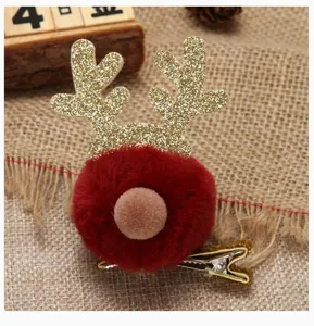 Detailed view of a Christmas reindeer antler hair clip with a red pom pom and glitter antlers.