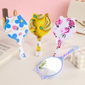 Süße handgehaltene Spiegel in Katzenform mit bunten Blumen- und Bananenmustern für Make-up.