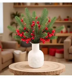 Detailed view of artificial Christmas pine branch with glossy red berries in a white vase