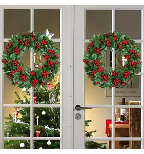 Pair of artificial Christmas wreaths with holly leaves and red berries on a white door