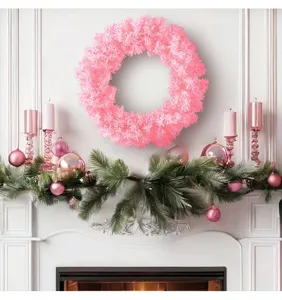 Détail d'une couronne de Noël rose vif accrochée sur une cheminée festive blanche.