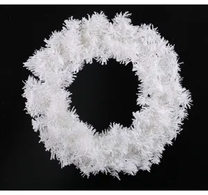 Gros plan d'une couronne de Noël artificielle blanche et duveteuse sur fond noir.