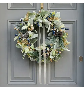 Detail view of a handcrafted lamb's ear leaf wreath with gold berries on a grey door