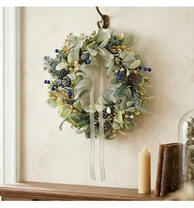 Detail view of artificial lamb's ear wreath with berries and pine cones hanging on a wall