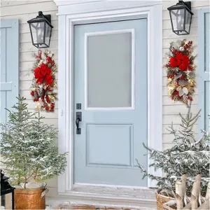 Festive Christmas teardrop swags with red bows and lights hanging on a light blue front door