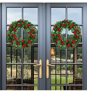 Detail view of two artificial Christmas wreaths with red berries on double glass doors